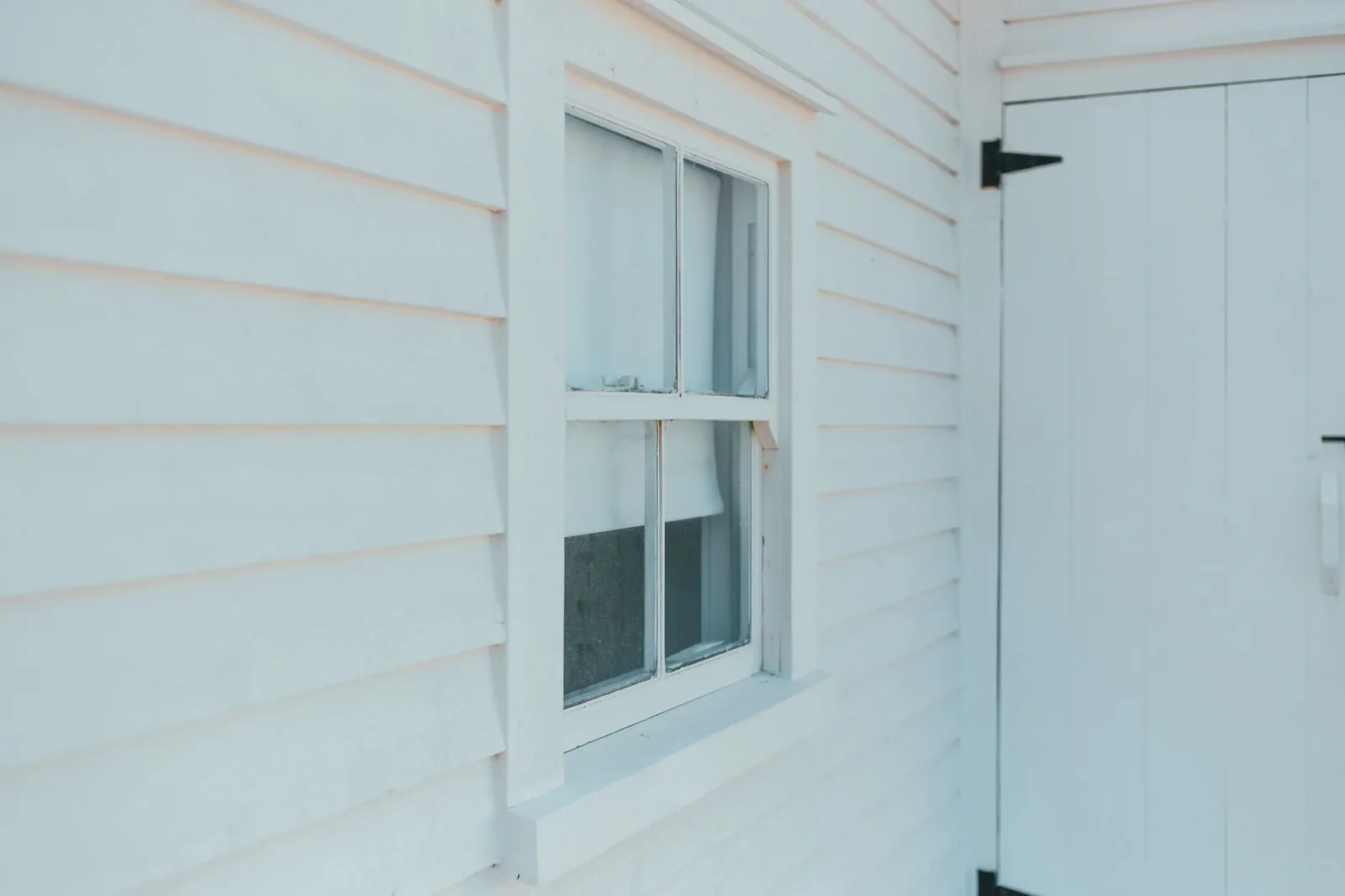 House siding cost per square foot varies by material, from white wood facade to metal panels