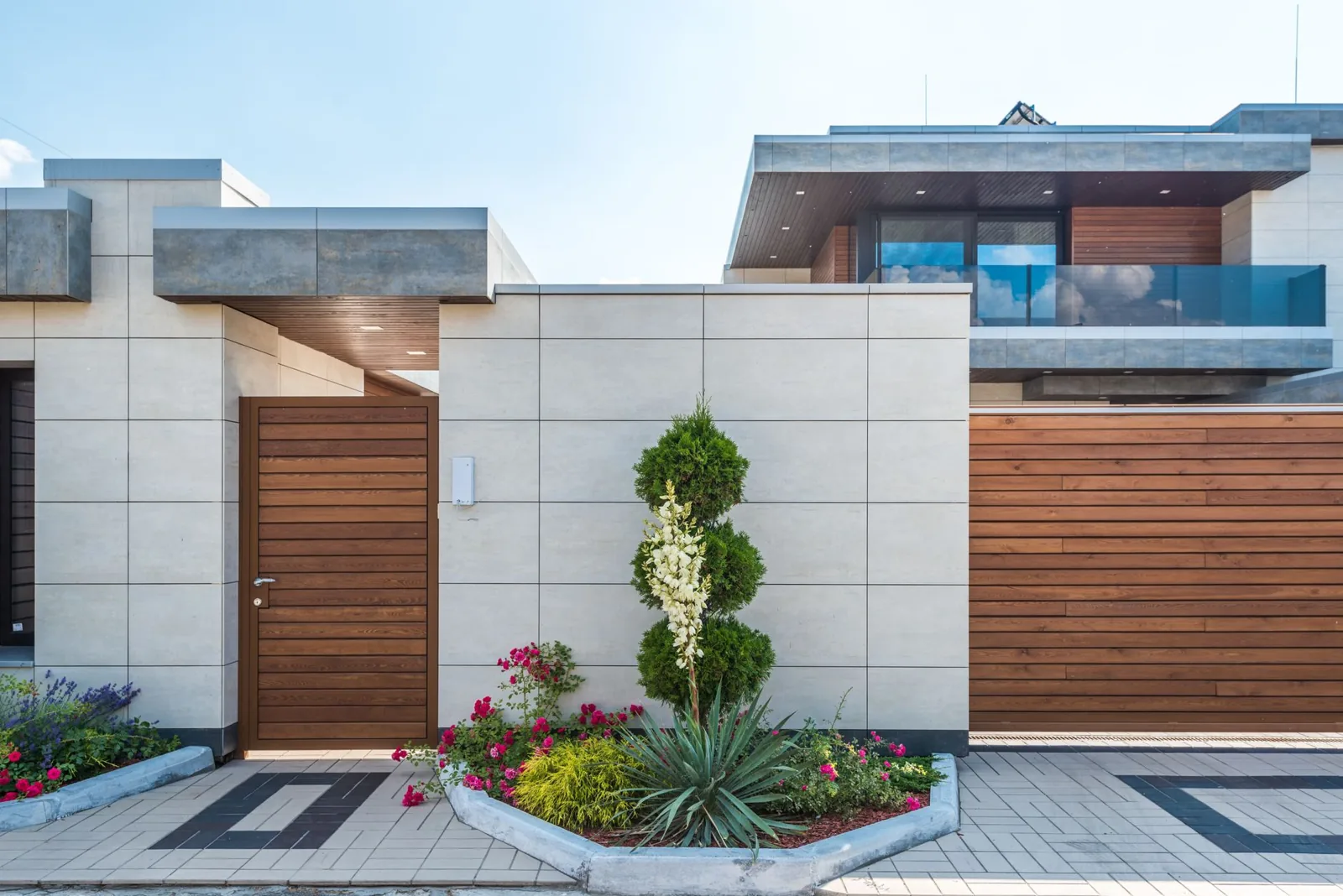 Curb appeal trends 2026 — contemporary house exterior featuring a wooden facade, entrance gate, and a vibrant garden