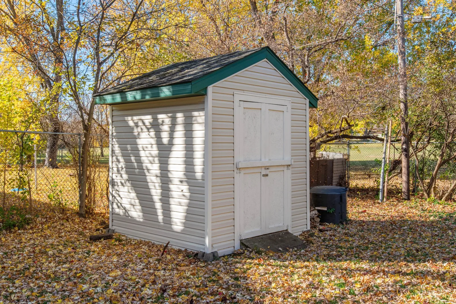 A backyard shed with siding surrounded by autumn foliage