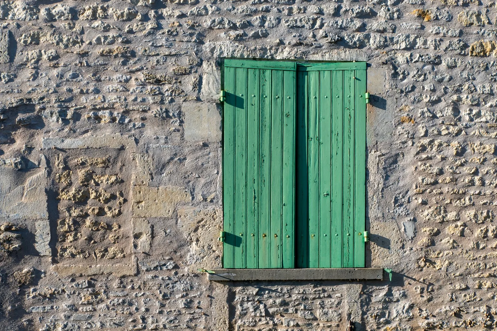 masonry paint vs limewash — old stone wall with closed shutters