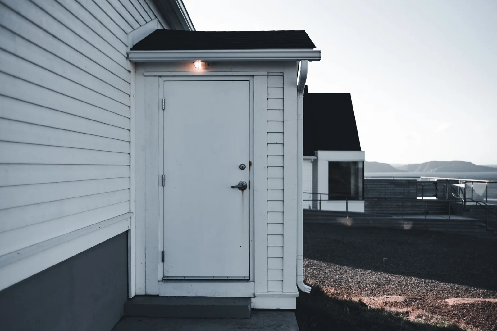 white siding and a minimalist entry door on a white house exterior