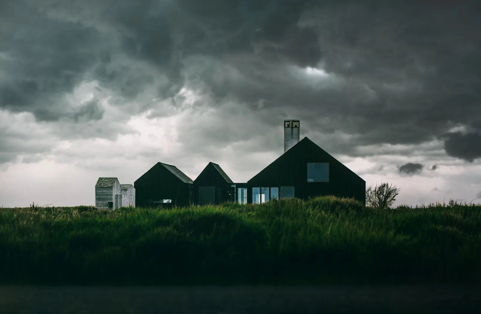 A modern farmhouse exterior with board and batten siding under storm clouds